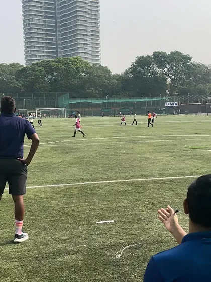 A coach observing the game from the sidelines, analyzing the play and preparing to give tactical feedback. This is coaching in action.