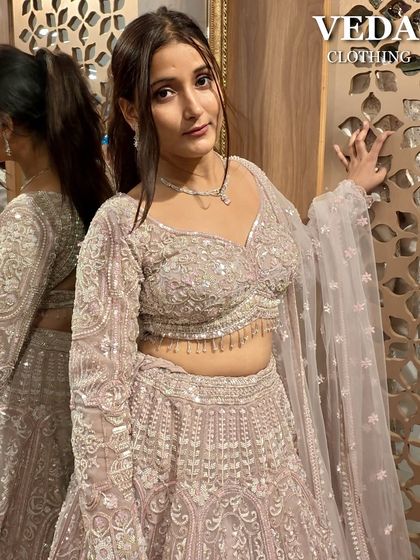 A close-up portrait in the pastel pink lehenga, highlighting the delicate embroidery on the full-sleeve blouse and the soft, romantic feel of the outfit.