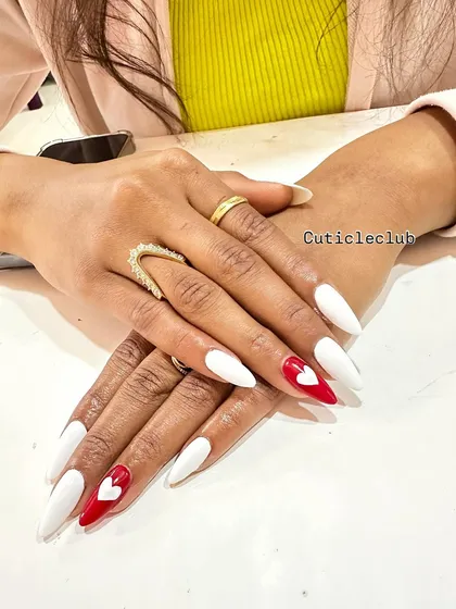 A bold and romantic design with sharp white stiletto nails and a vibrant red accent nail featuring a 3D heart.