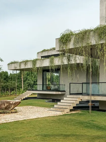 The home's tiered, concrete form is softened by cascading greenery, integrating the structure into the rolling landscape.