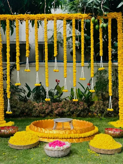 For this outdoor Haldi ceremony, I used traditional marigolds to create a vibrant and auspicious backdrop. The setup includes a central seating area and baskets of fresh petals, perfect for pre-wedding rituals and photos.