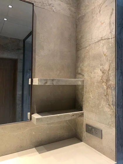 A bathroom niche with floating stone shelves. The design is minimal and functional, but the use of a single, continuous material for the walls and shelves creates a seamless and luxurious feel.