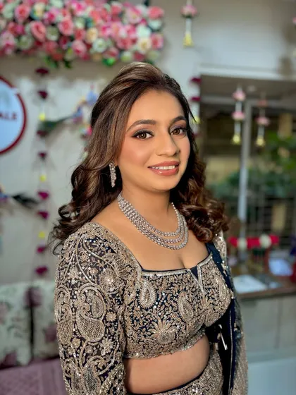A happy, smiling portrait of the bride. The makeup is designed to look stunning both in person and under the bright lights of a Sangeet night.