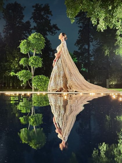 An artistic shot capturing the bride's reflection. This image highlights the ethereal quality of the entire look, from the makeup to the flowing cape.