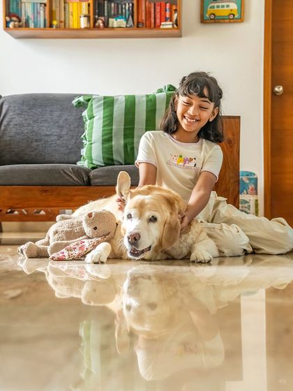 A girl and her senior Labrador, Mhysa, share a happy moment on the floor. The reflection on the marble adds a beautiful touch to this candid shot of friendship and comfort during an at-home session.