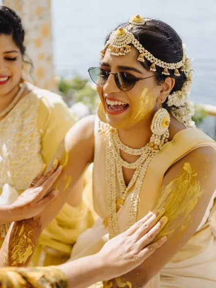 A bride enjoying her Haldi ceremony, surrounded by friends and family. We focus on creating a comfortable and happy environment so you can soak in every moment of these special rituals.