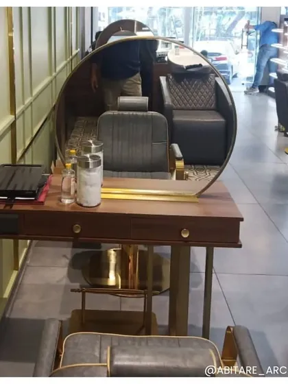A close-up of a custom styling station, showing the detail of the round brass mirror and wooden vanity. This highlights our focus on bespoke furniture and high-quality materials to elevate the design of a commercial space.