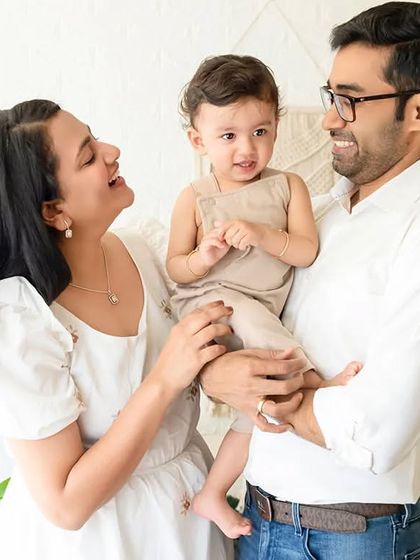 A candid moment where parents smile at each other while holding their baby.
