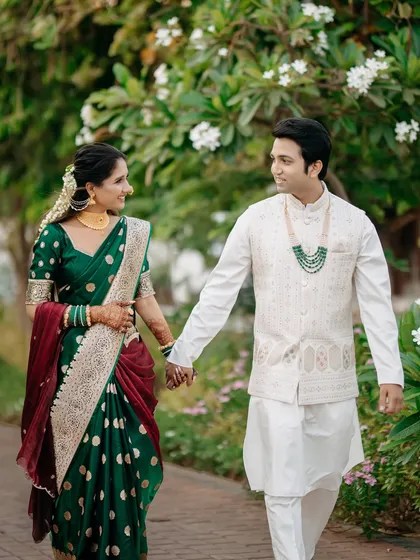 A candid moment of a couple walking hand-in-hand through a lush garden. Dressed in beautiful Maharashtrian attire, their shared glance speaks volumes, reflecting the natural, unscripted joy I love to capture.