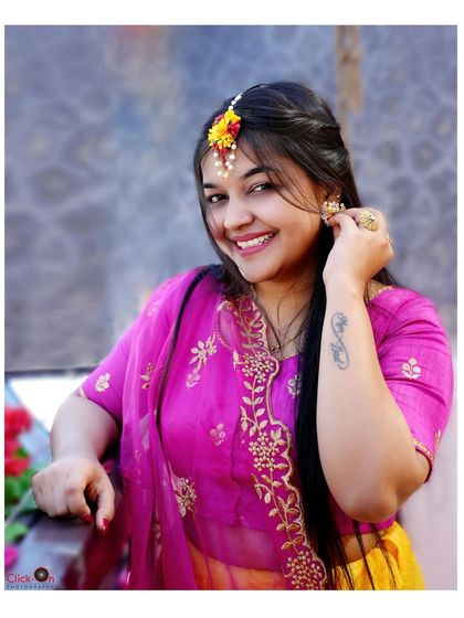 A joyful portrait of a bride-to-be at her Haldi ceremony. The bright pink and yellow outfit perfectly complements the festive mood.