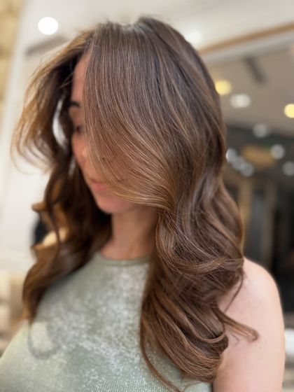 A beautiful still of a no-bleach balayage with soft, flowing waves. The caramel and brown tones blend perfectly for a natural, sun-kissed effect.