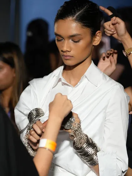 The final moments of prep before a model hits the runway. Our team works together to ensure every element, from makeup to accessories, is perfect.