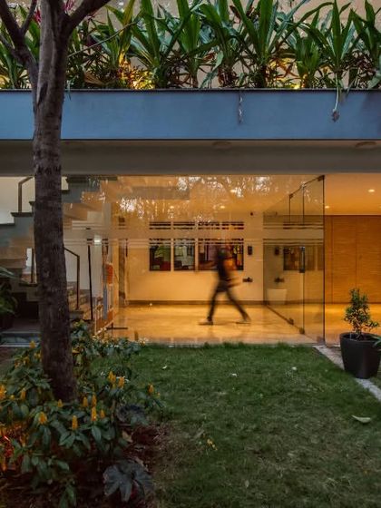 The entrance to this office space is designed to feel open and connected to the outdoors. A glass facade and lush landscaping create a welcoming transition from the garden into the building.