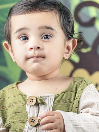 A close-up portrait from a jungle-themed shoot, capturing a sweet and curious expression.