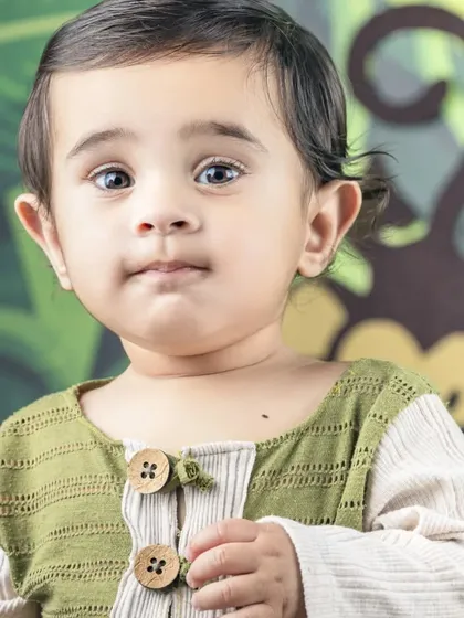 A close-up portrait from a jungle-themed shoot, capturing a sweet and curious expression.