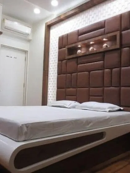 This bedroom features a unique, curved platform bed and a geometric padded headboard. The built-in niche with spotlights is perfect for displaying small decorative items.