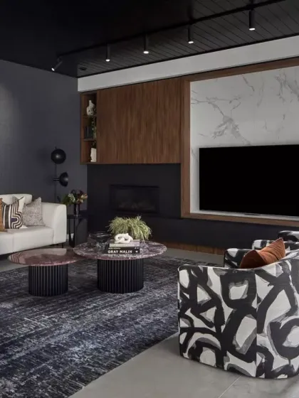 A bold yet sophisticated living space from our Queensland, Australia project. The deep, moody palette is balanced with rich textures, warm wood, and luxe marble. Statement accent chairs with abstract patterns add a dynamic visual rhythm.