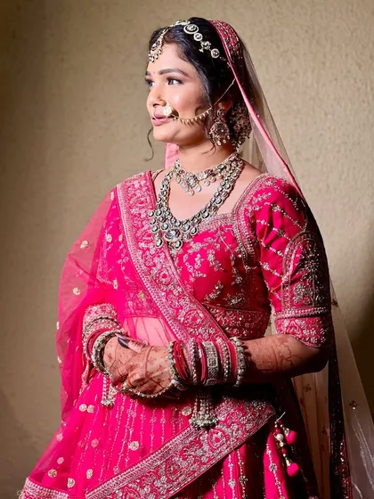 A beautiful bride in a pink lehenga, her look perfected with a layered Kundan necklace and matha patti.