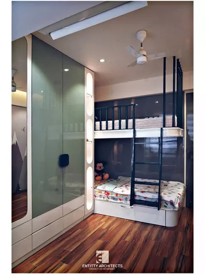 This kids' room is designed for both play and rest. It features a custom-built bunk bed with an integrated ladder and a full-wall wardrobe with sleek glass shutters and open display niches.