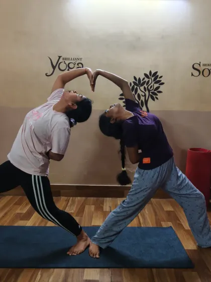 A beautiful expression of connection in a partner reverse warrior pose. This posture creates a shared heart-opening stretch and encourages synchronized breathing and movement.