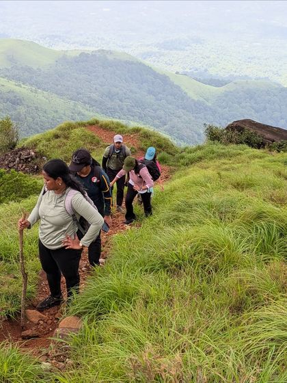 Trekkers making their way up a grassy slope on the Kurinjal trail.