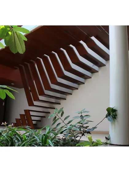 A detail of the sculptural staircase in the 'Boxed In House', fabricated from teakwood recycled from the original demolished structure. This element is a testament to our commitment to material honesty and sustainable practices, transforming reclaimed materials into a central, artistic feature of the home.