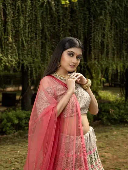 A lovely bridal portrait taken under the soft shade of willow trees. The gentle light and natural green backdrop complement her elegant lehenga, creating a soft and romantic image.