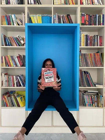This rectangular blue reading nook offers a bold pop of color in a monochromatic library. It is a simple yet effective way to create a designated, cozy space for reading that feels both integrated and special.