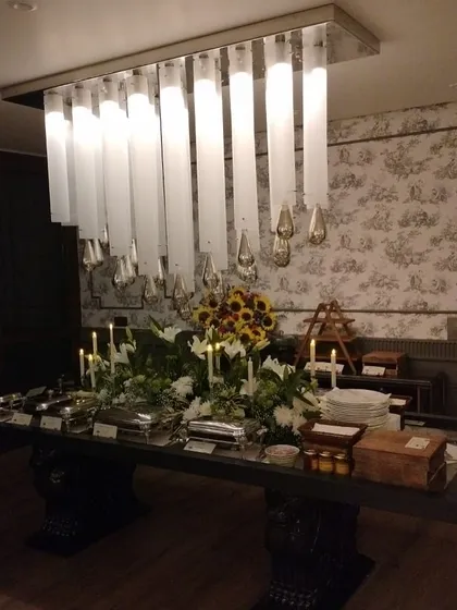A stunning, candlelit buffet table set under a modern chandelier in a private residence. This is how I create a feast for the senses.
