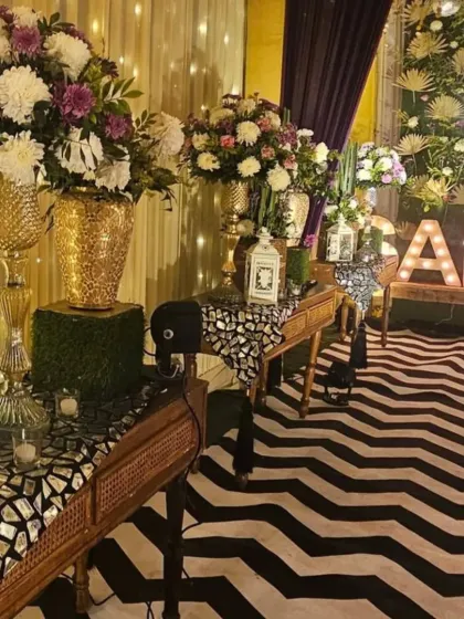 This Sangeet setup features a bold black and white chevron floor runner, mirrored console tables, and large floral arrangements. Marquee letters spelling "SANGEET" add a personalized and festive touch.