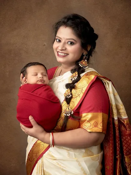 A proud mother in a traditional South Indian saree holds her sleeping newborn. This portrait is a beautiful blend of cultural heritage and the timeless love for a new child.