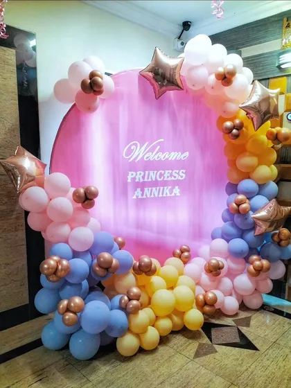 A 'Welcome Princess' photo booth with a circular pink backdrop and a multi-colored pastel balloon garland.
