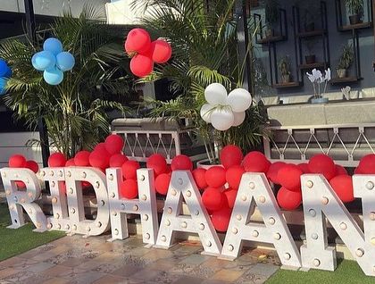 Large, light-up letters spelling out the birthday boy's name, placed outdoors to welcome guests to the party venue.