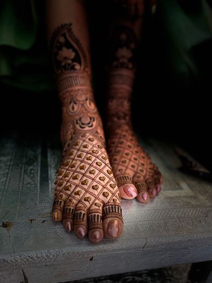 A beautifully composed shot of a bridal foot mehandi with a heart-filled jaali pattern, showing the rich dark stain.