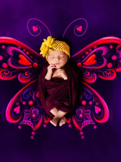 A digitally enhanced butterfly theme, with vibrant, glowing wings added to the portrait of a sleeping baby.