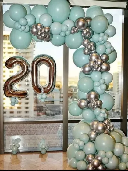 A budget-friendly and stylish arch decoration for a 20th birthday. The combination of pastel green and chrome silver balloons creates a modern and chic look, perfect for an apartment with a view.