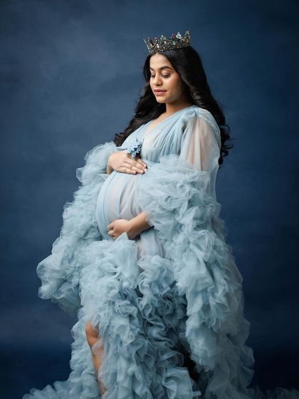 A regal portrait featuring a voluminous blue ruffled gown and a delicate crown, fit for the queen that every mother is.