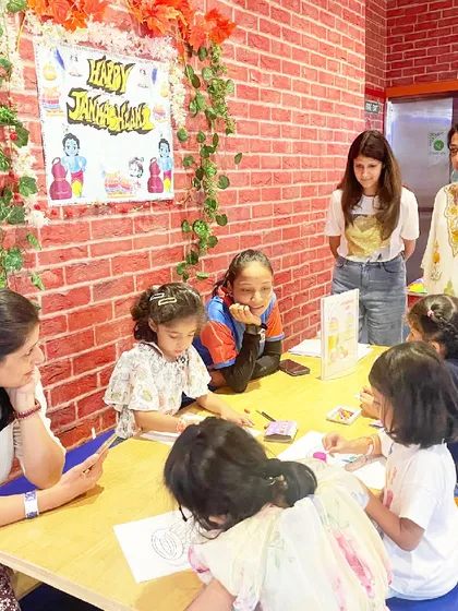 Families and children are engrossed in a coloring activity at our Janmashtami celebration.