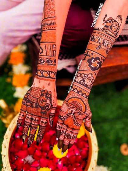 A view of both hands, one with a large elephant design and the other with intricate traditional patterns.