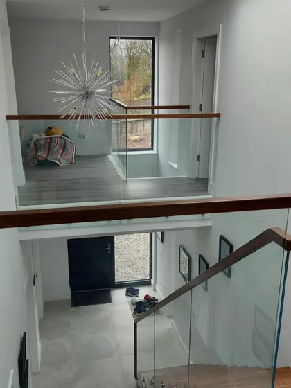 The view from the top landing, showing how the staircase and glass balustrade integrate with the upper floor. This maintains an open and connected feeling between levels.