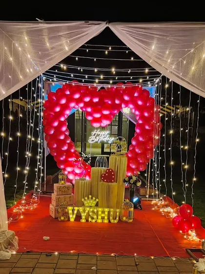 We specialize in creating unforgettable romantic surprises. This stunning outdoor cabana setup features a heart-shaped balloon arch, a red carpet entrance, and magical fairy lights, perfect for a birthday or anniversary celebration.
