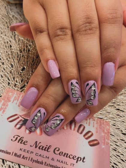 A beautiful butterfly design on square-shaped nails. The soft lavender polish is complemented by accent nails with hand-painted butterflies filled in with sparkling crystals.