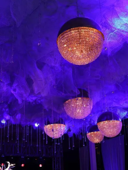 A detailed shot of the celestial-themed ceiling decor, showing the texture of the cloud-like fabric and the warm glow of the hanging spherical crystal lights.