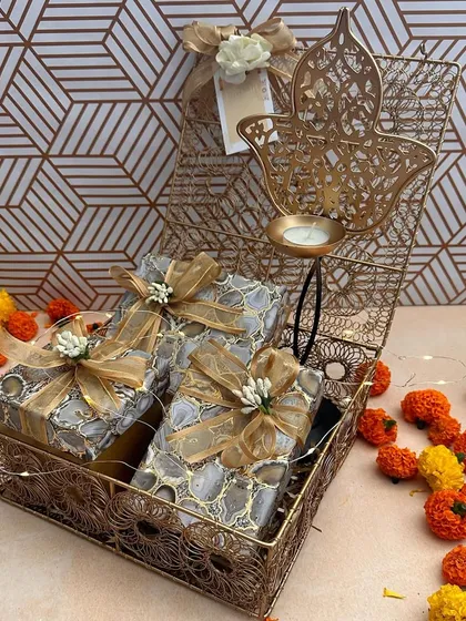 A perfect example of a compact yet luxurious Diwali gift. This hamper, set in a wireframe basket, includes beautifully wrapped agate-print boxes and a Hamsa-shaped T-light holder, ideal for corporate gifting or as a thoughtful present for friends.