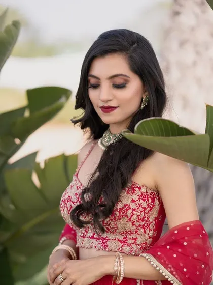 A close-up of our client, showcasing the intricate embroidery on her red lehenga blouse and her beautiful makeup.
