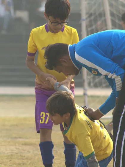A coach offers a helping hand to a player, demonstrating the supportive environment of our league.