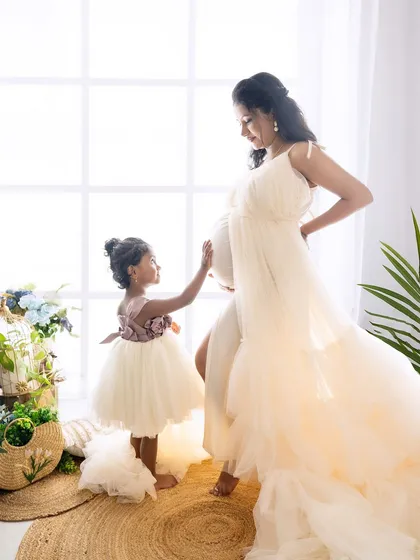 A heartwarming family maternity photo where a big sister-to-be gently touches her mother's baby bump. This captures the sweet anticipation and growing love within the family.