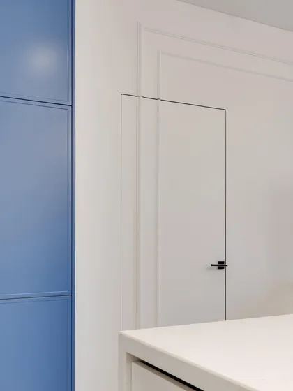 A detail shot showing the clean lines of a hidden door and the pop of color from an adjacent blue cabinet.