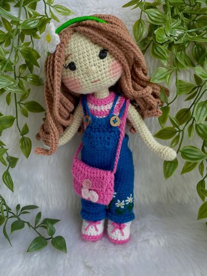 A closer look at the doll in her first outfit. The details on the overalls, like the little embroidered daisies, make her extra special. The clothes are designed to be easy for children to put on and take off.