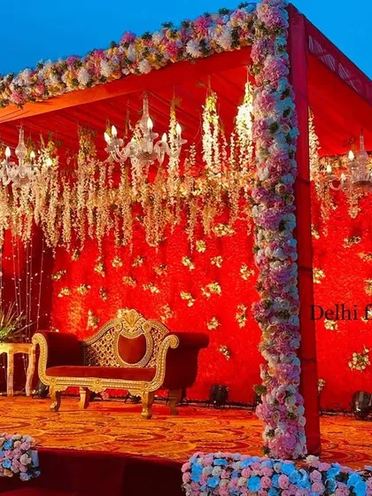 A stunning red and gold stage, featuring a backdrop of red roses and a ceiling of hanging floral strings and chandeliers.